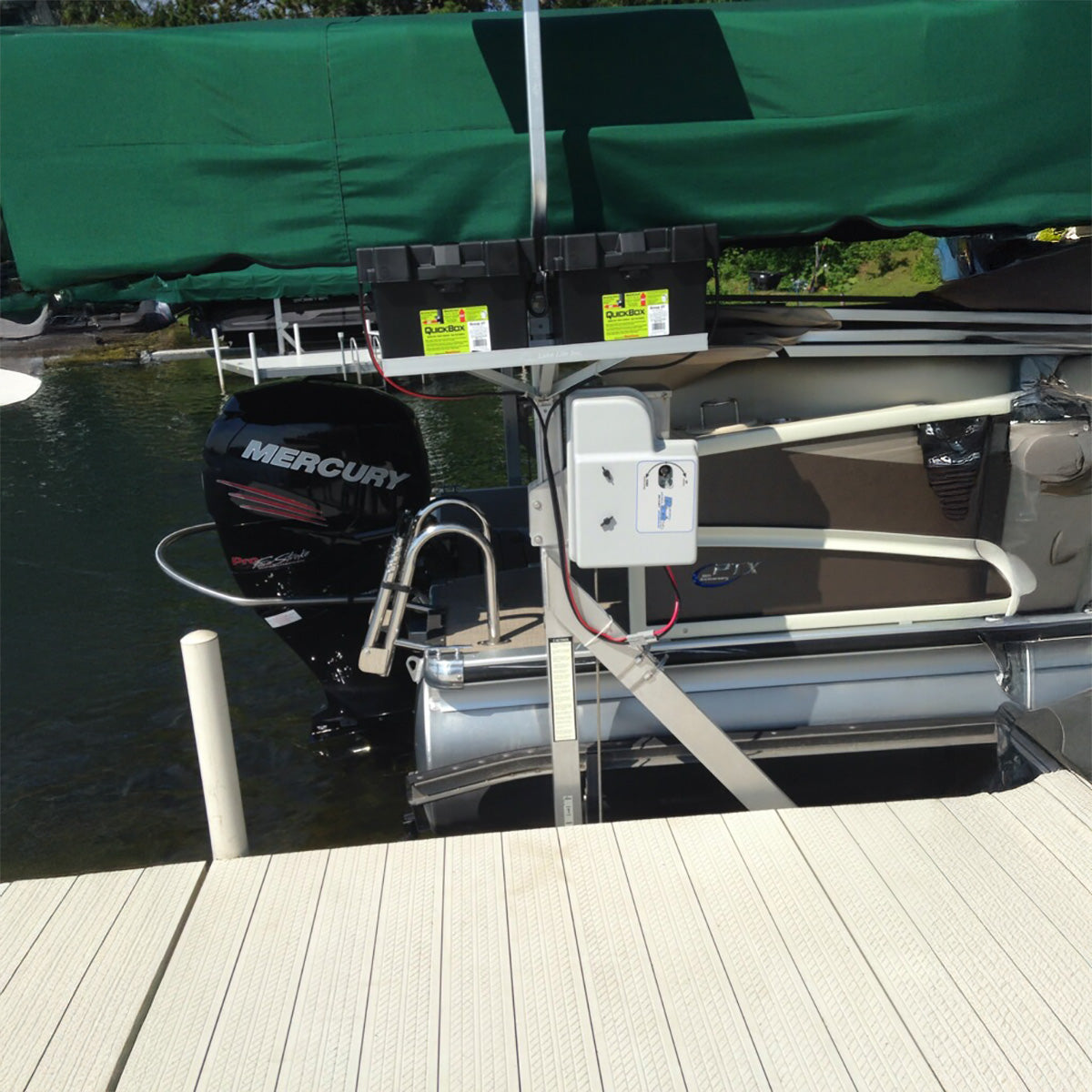 Boat docked at a pier with a Mercury outboard motor, green cover in the background.