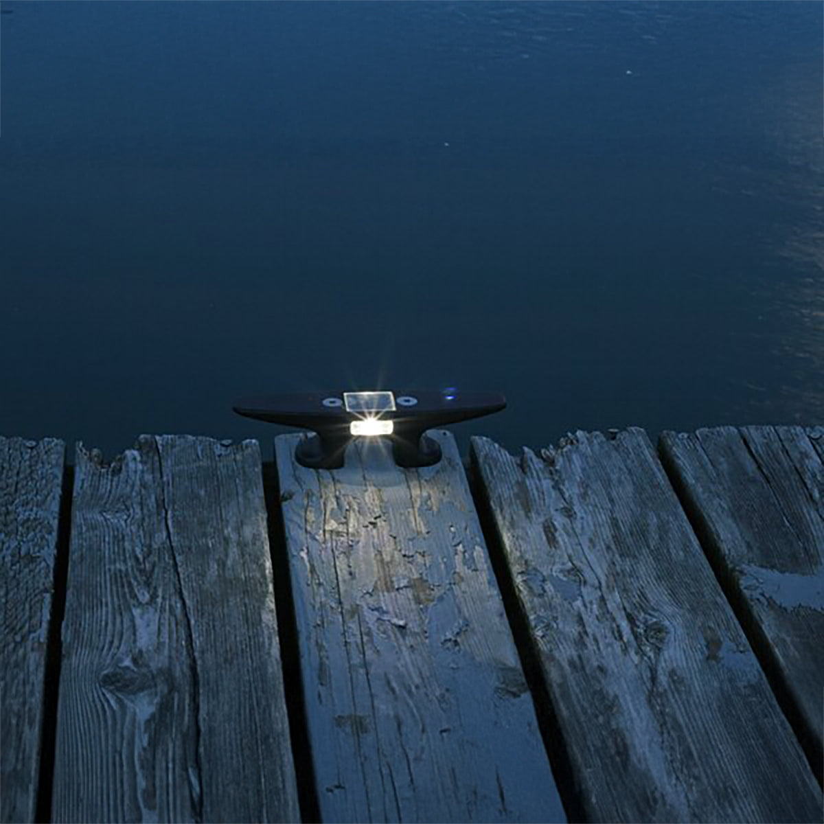 Light fixture on a wooden dock by a body of water at night