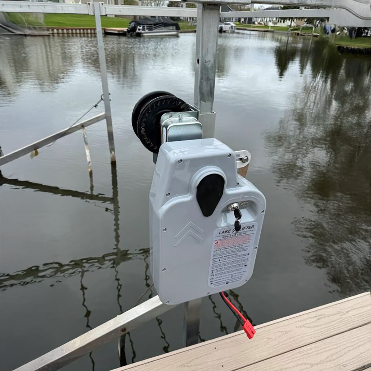 White electrical box with red cord on a dock by a body of water