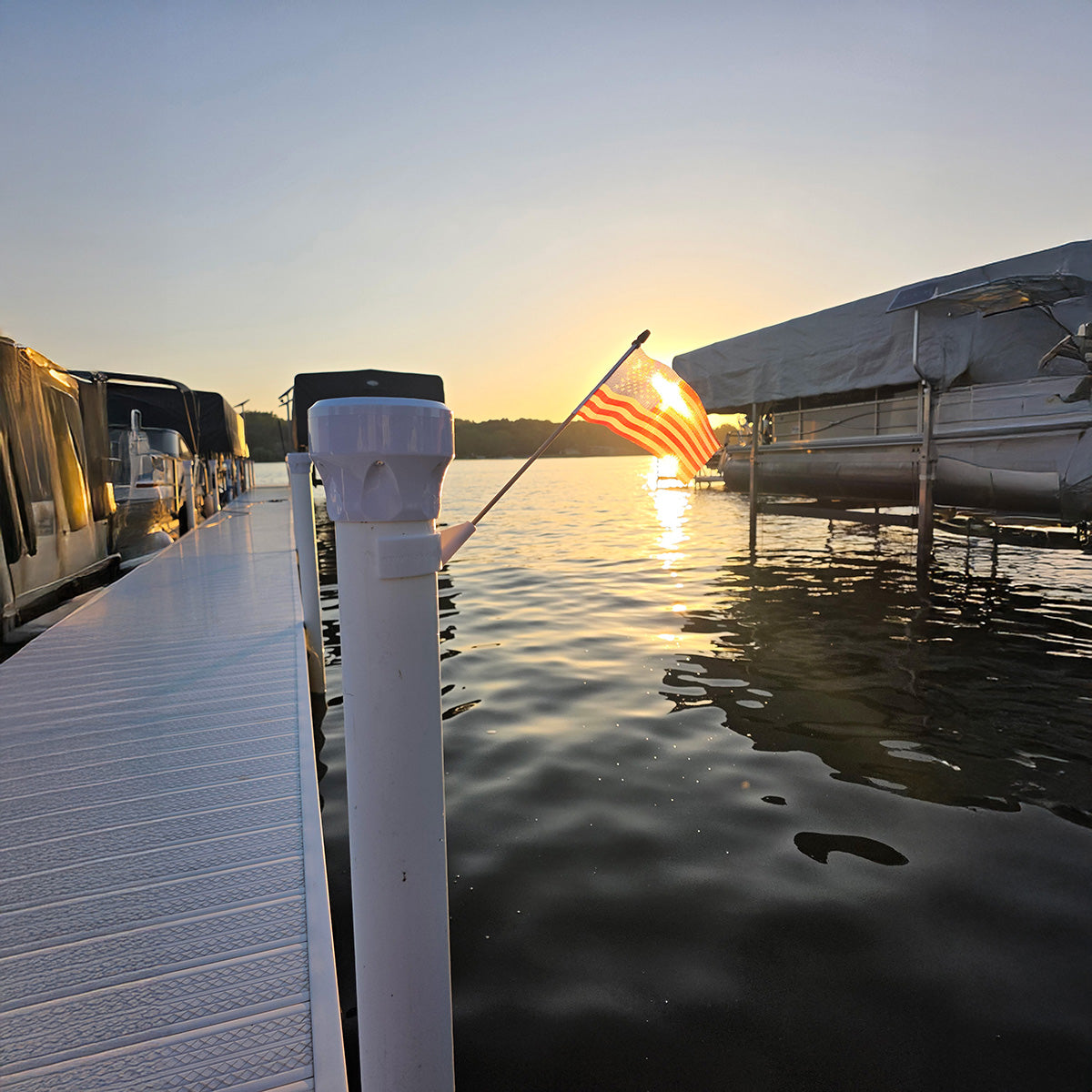 Dock with boats and an American flag at sunset