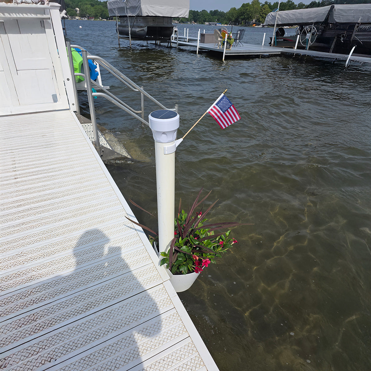 Dock with American flag and potted plant, water in the background