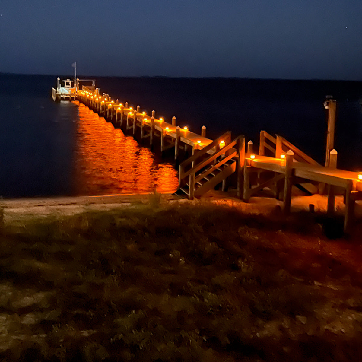 Wooden pier with lights extending into the water at night