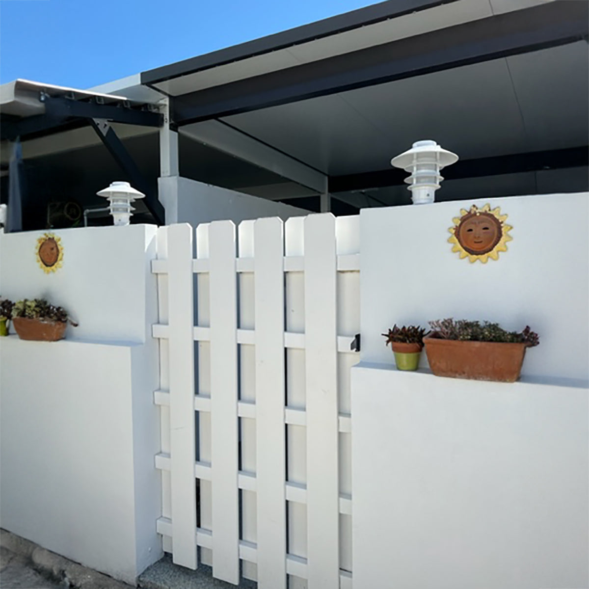 White lattice panel with decorative elements on a white wall outdoors.
