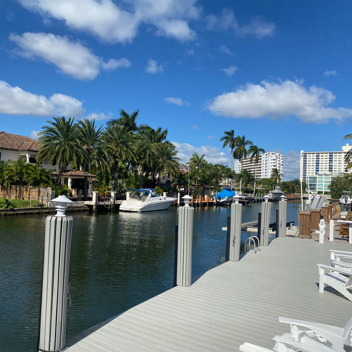 Marina scene with boats and a dock under a blue sky with clouds.