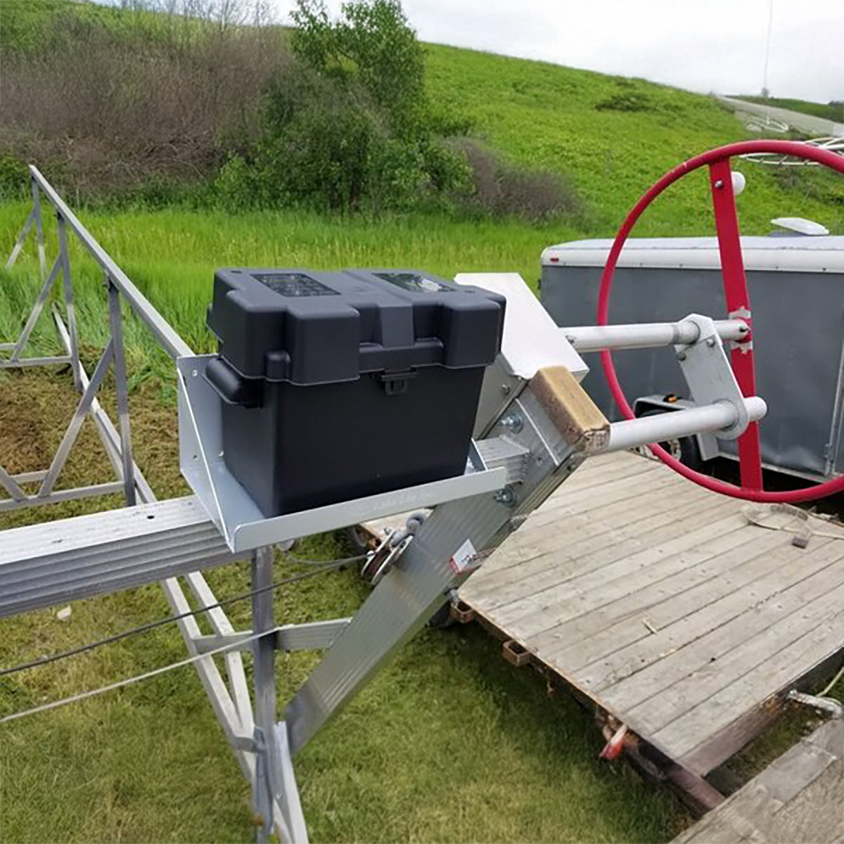 Single cantilever battery tray holding a battery box on a boat lift