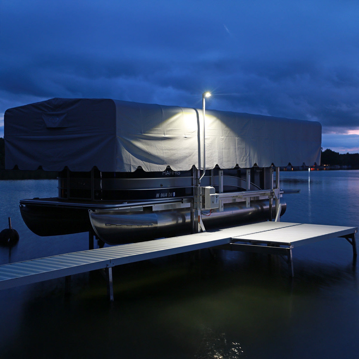 Boat docked at a pier under a dark sky with a light illuminating the area.