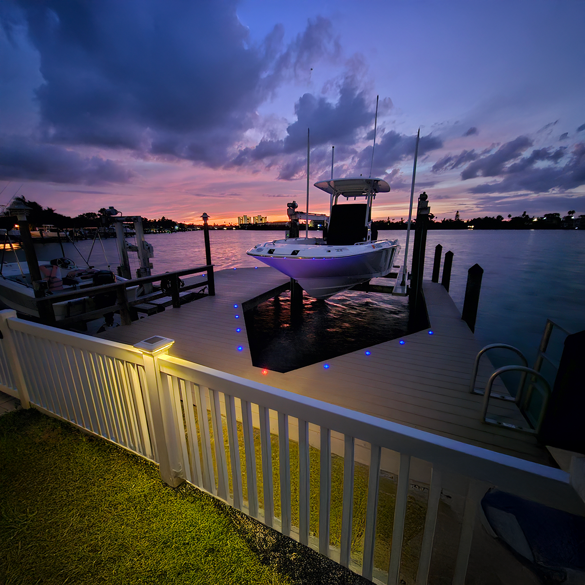 Solar dock dots lighting a dock railing beside boats at sunset