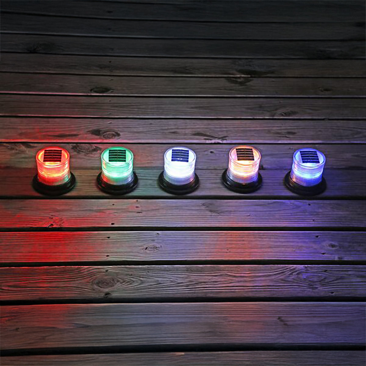 Six solar marine lights glowing in different colors on a dark wooden dock
