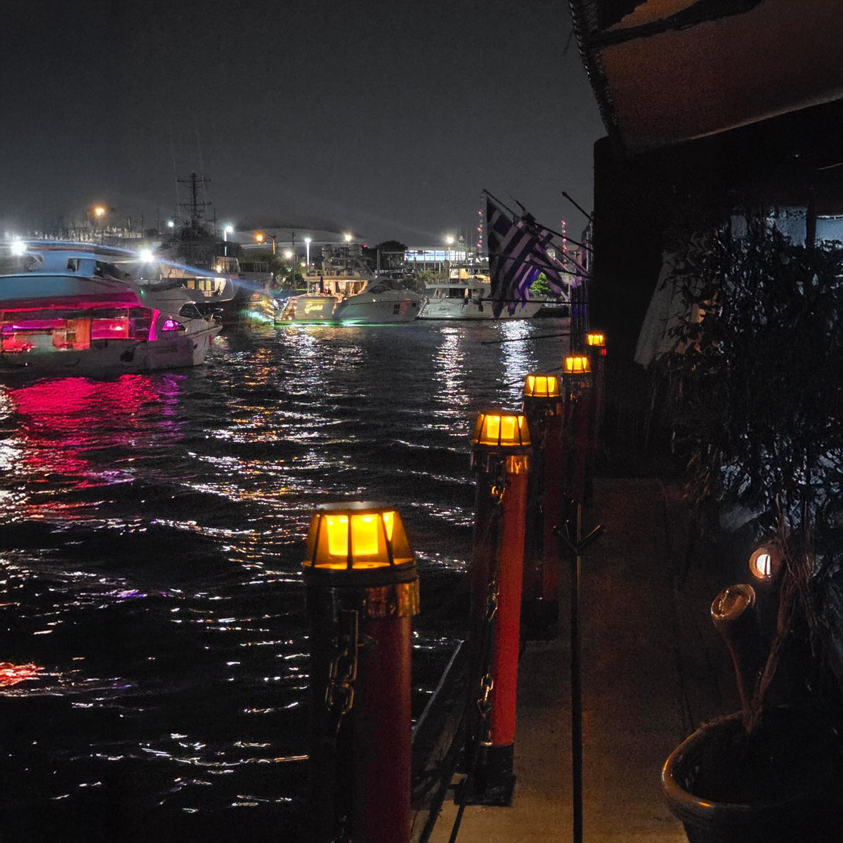 Nighttime view of a waterfront with boats and illuminated solar piling lights.