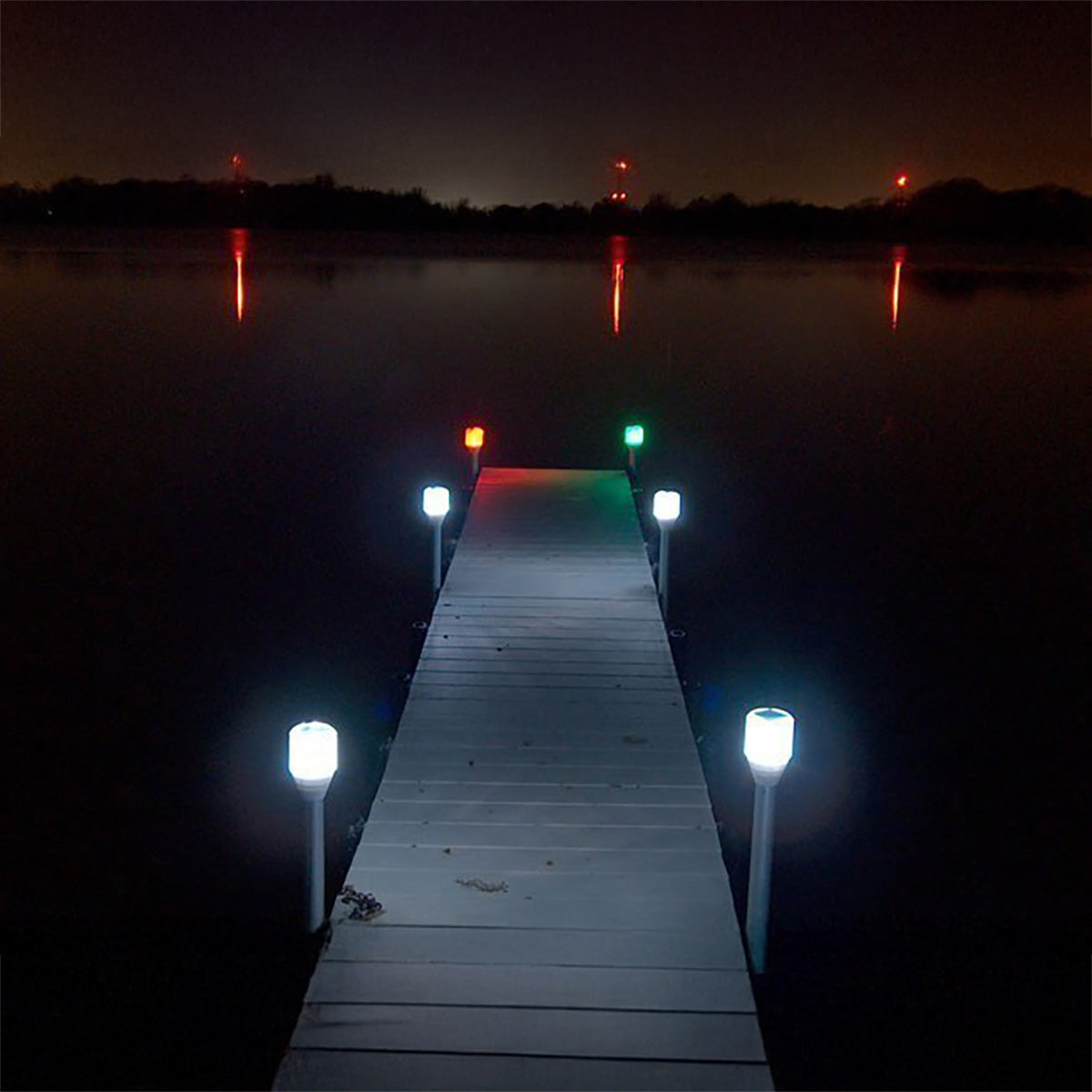 Wooden dock extending into a body of water at night with illuminated lights.