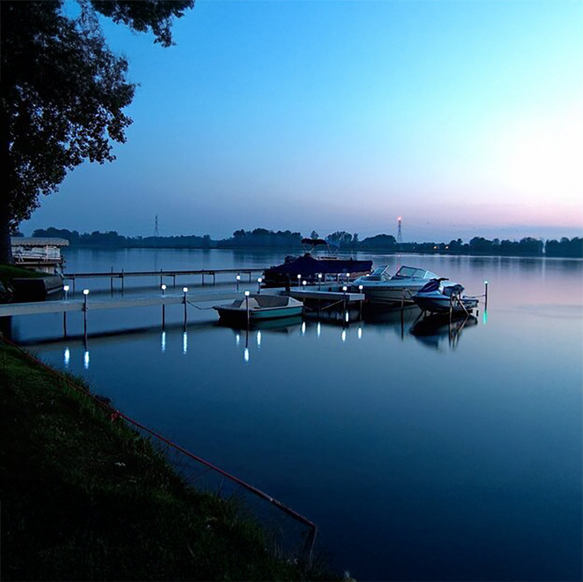Boats docked at a pier on a calm lake at dusk.