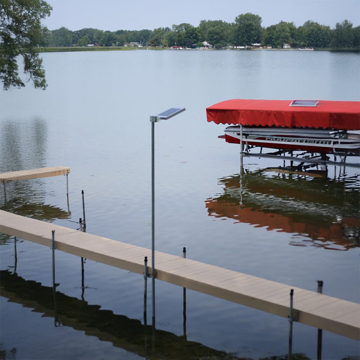 Dock with a red canopy and solar light on a calm lake with trees in the background
