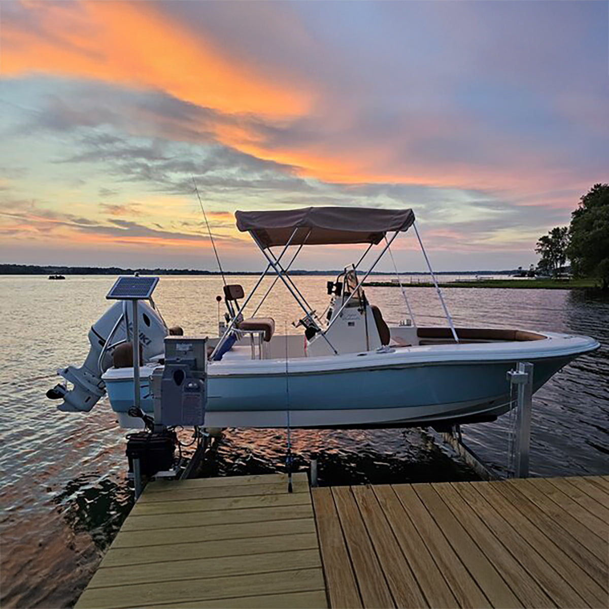 Boat docked at a wooden pier with a colorful sunset sky.