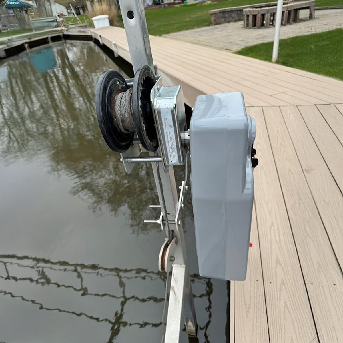Marine winch on a dock with water and grass in the background