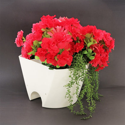 White elephant-shaped planter with red flowers and green leaves on a dark background