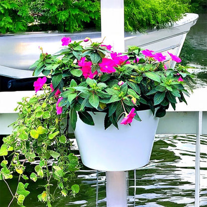 White planter with pink flowers on a boat in water