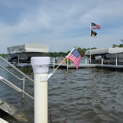 Dock with boats, American flags, and a light post in the water.
