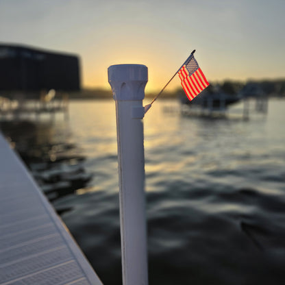 American flag on a pole with a sunset over water in the background