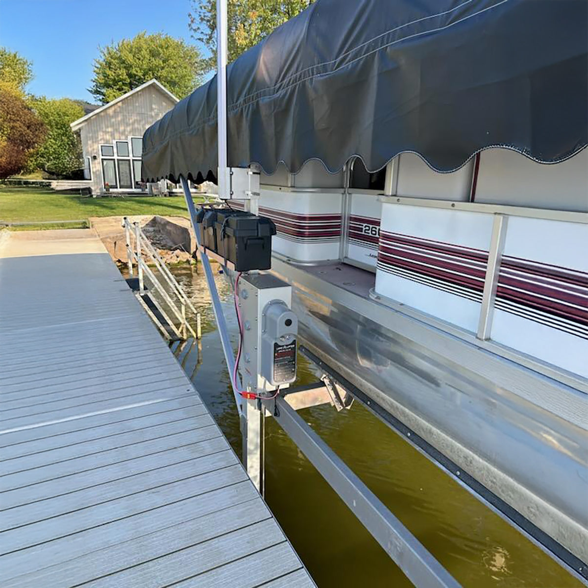 Pontoon boat with an awning on a dock by a house