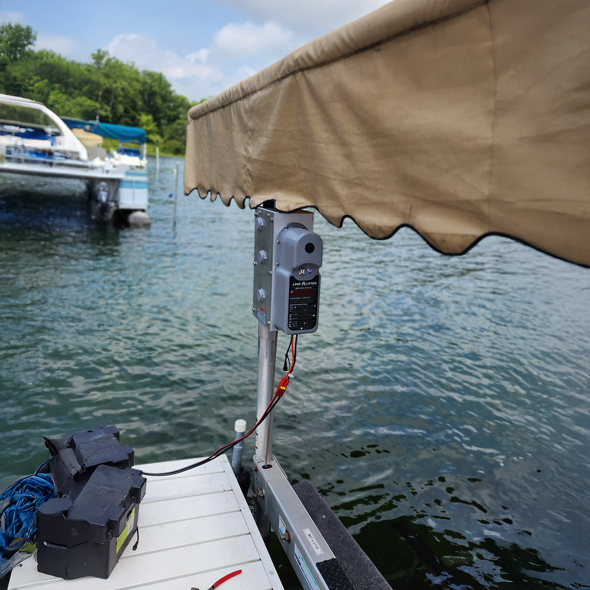 Boat docked at a marina with an awning and electrical components on a sunny day.