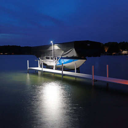 Boat on a dock under a dark blue sky with a light illuminating the scene.