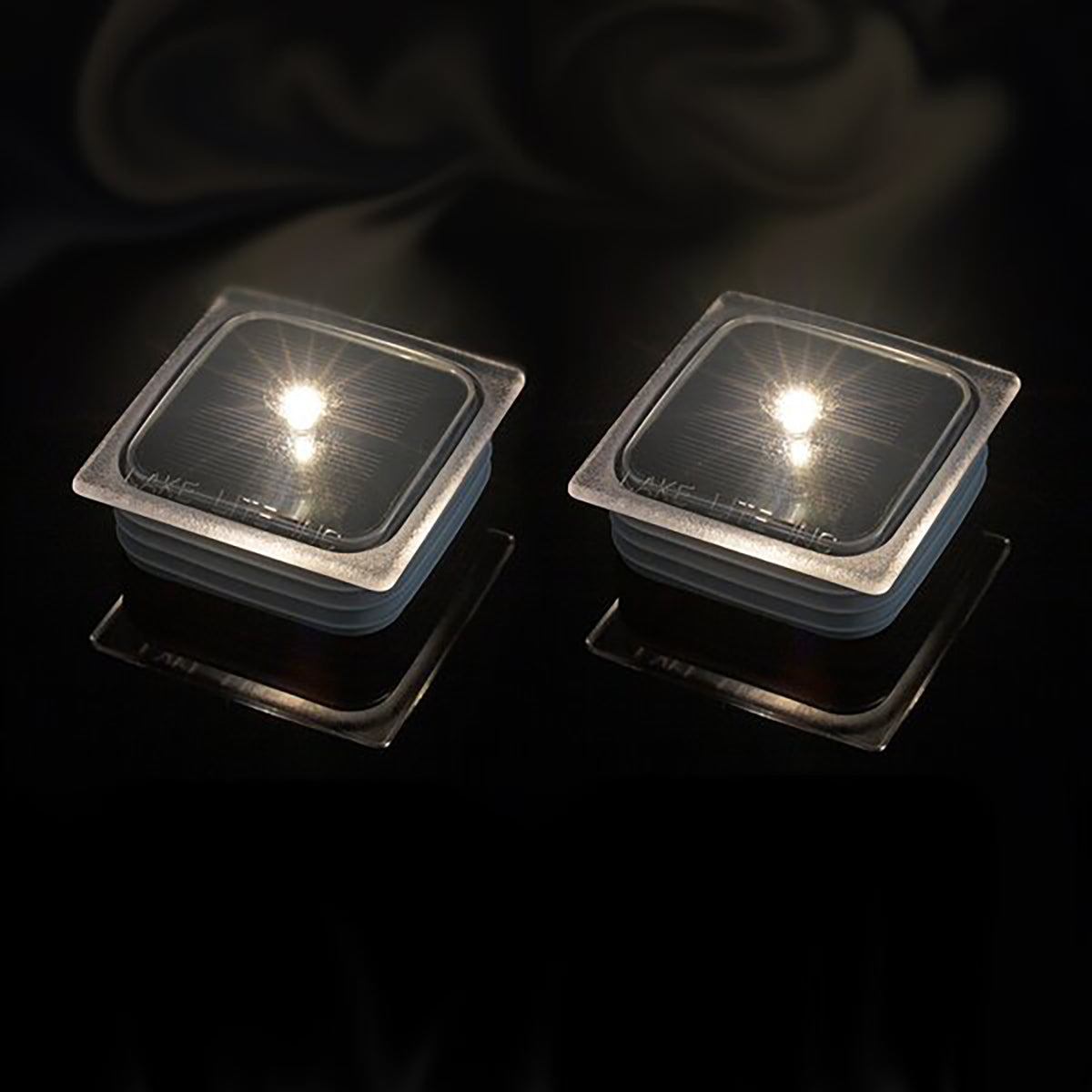 Two square solar dock caps for ShoreMaster Infinity docks glowing white at night