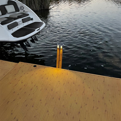 White boat on water near a wooden dock with two lights.