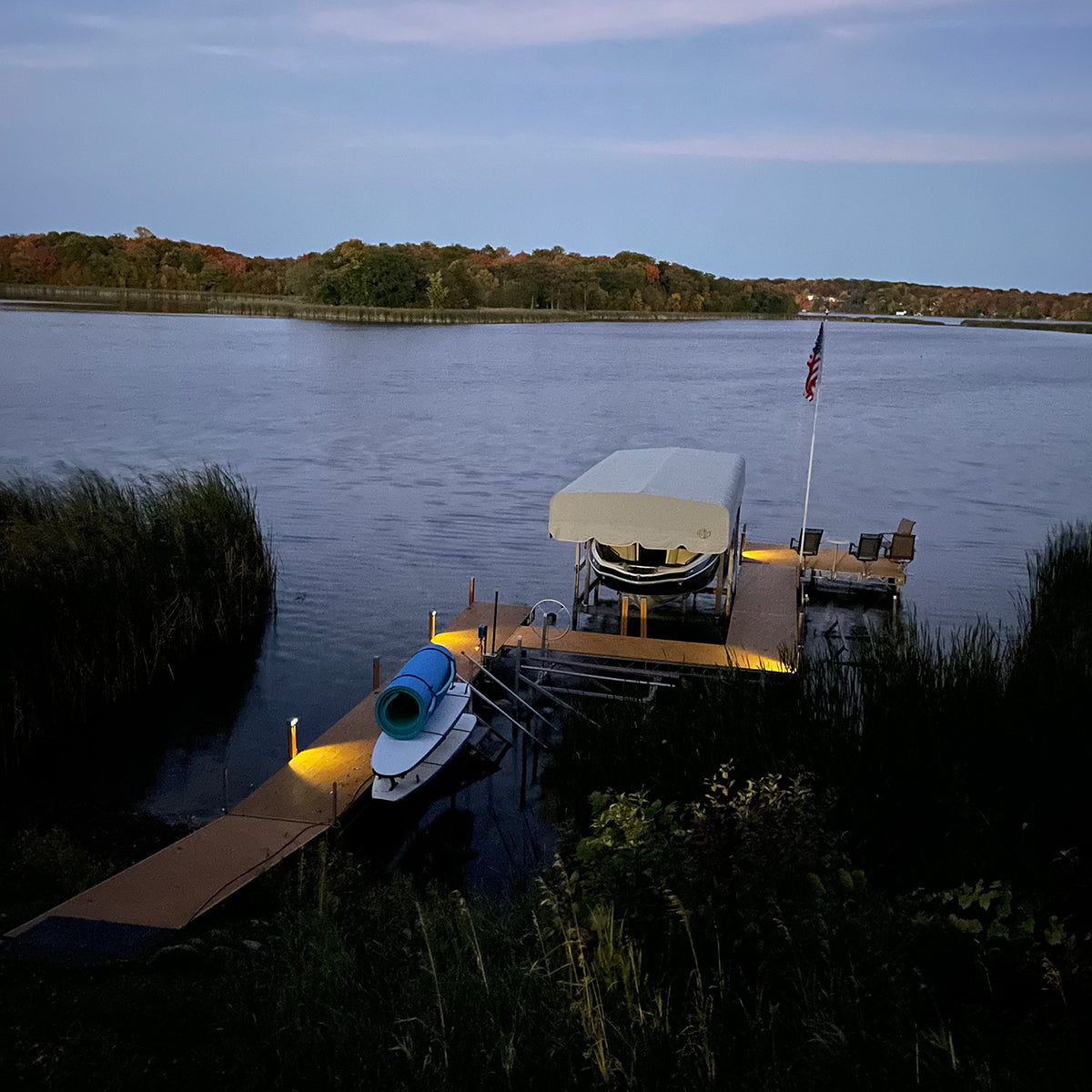 Dock with boats and a flag on a lake at dusk