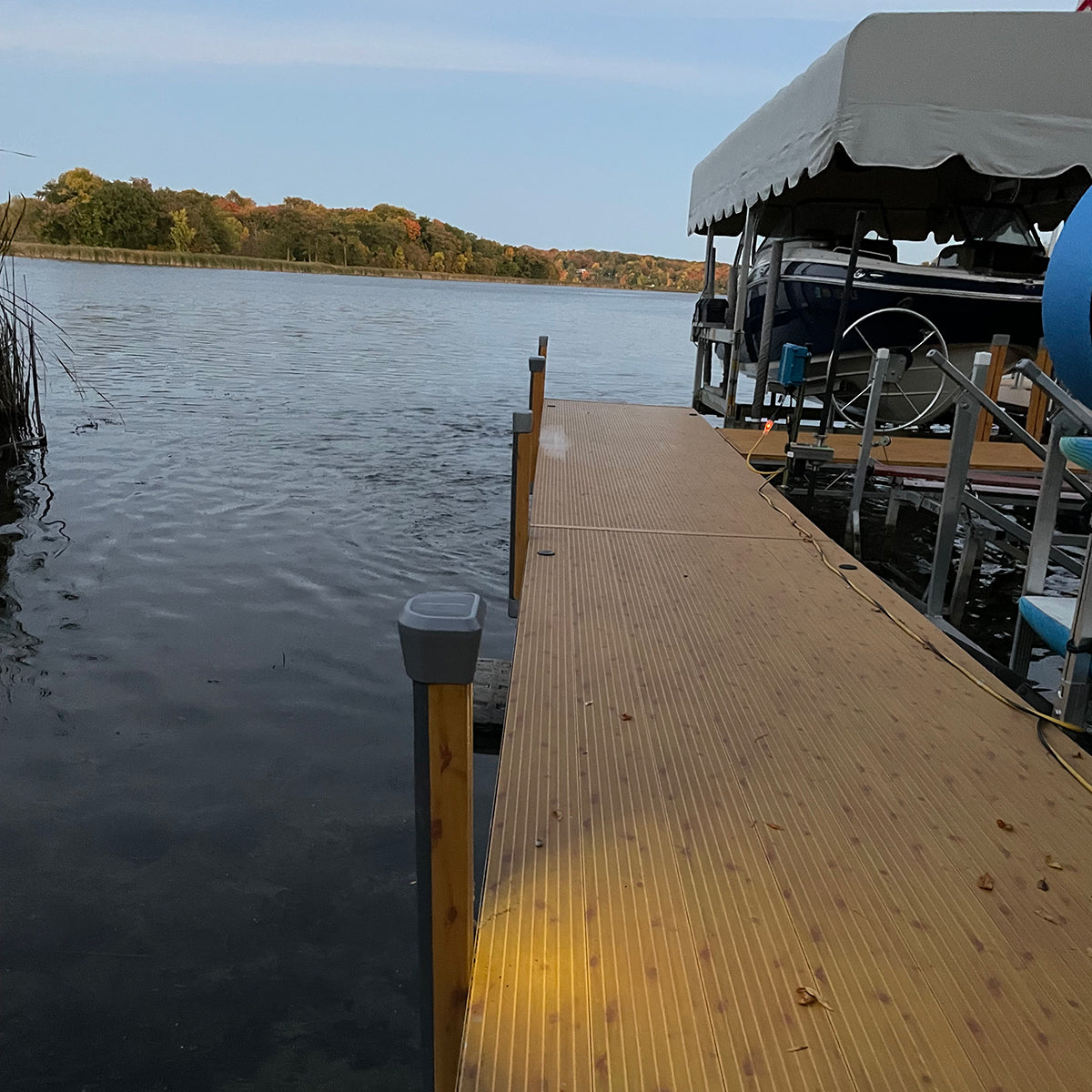 Wooden dock extending into a lake with a boat and canopy in the background.