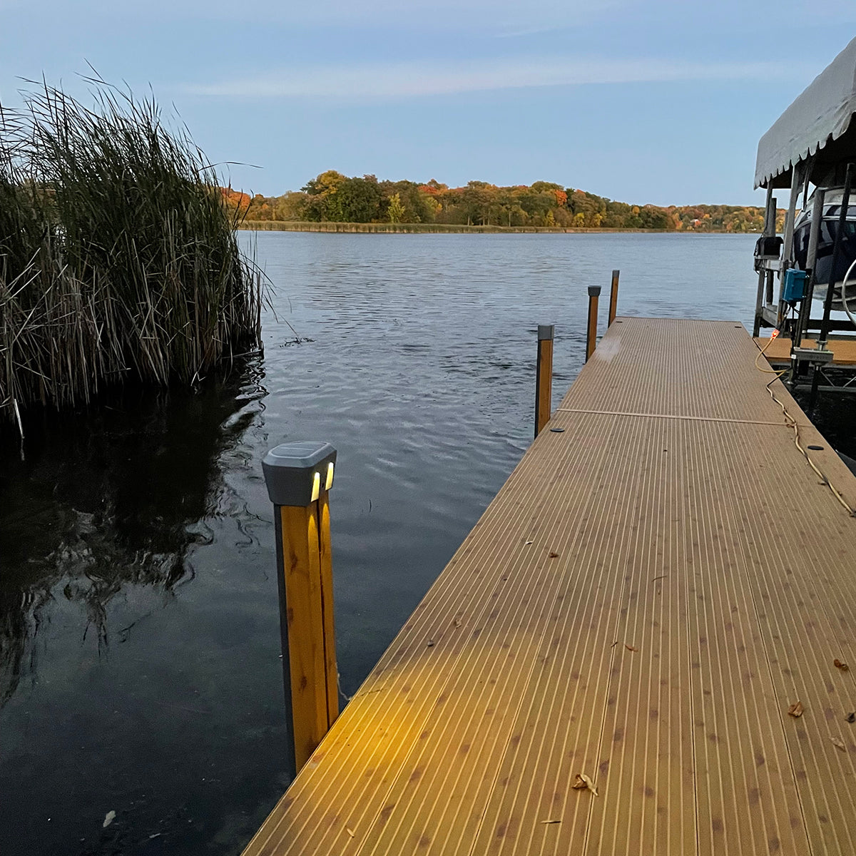 Wooden dock extending into a calm lake with trees and clear sky in the background