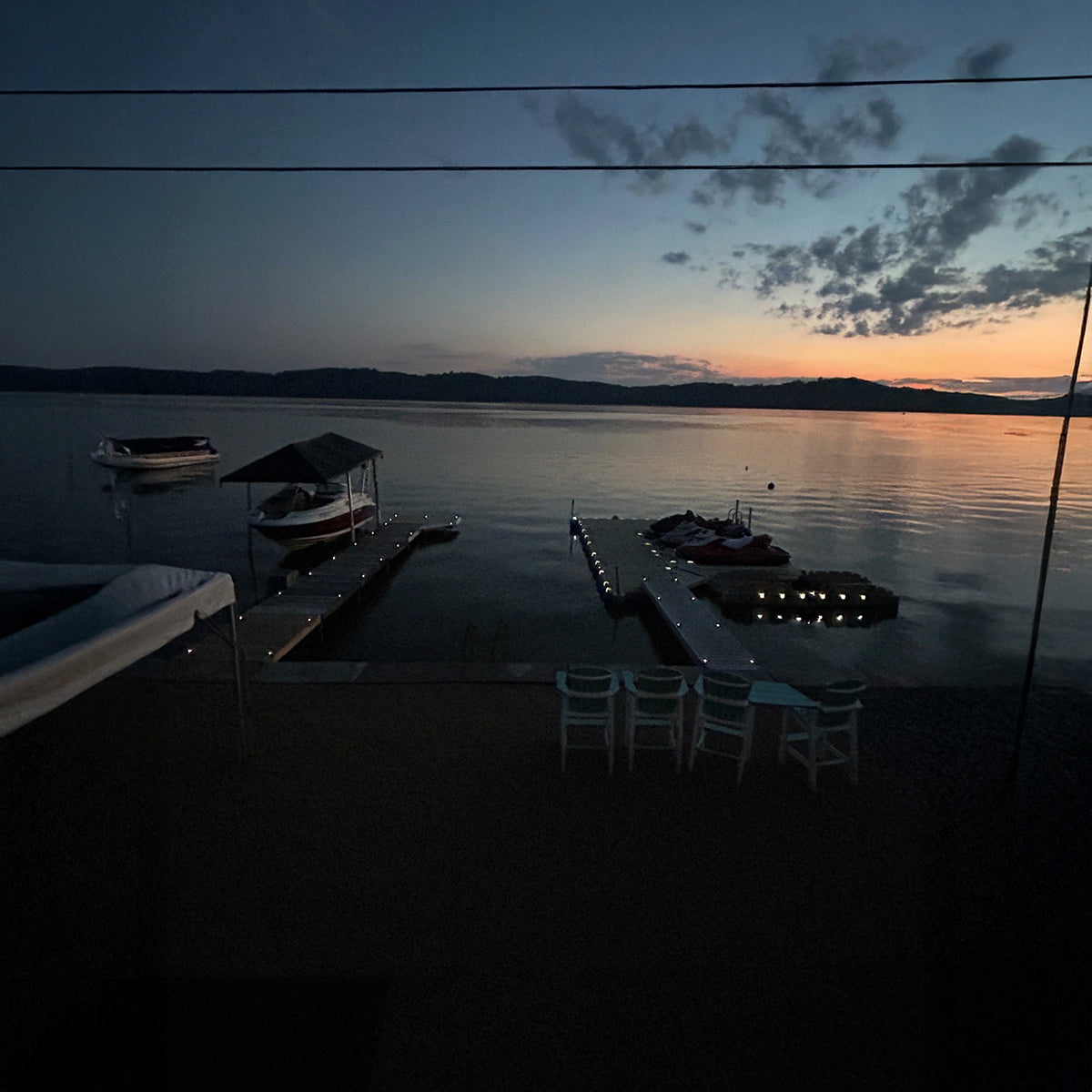Dusk scene at a lakeside with boats and docks.