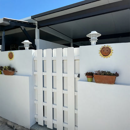 White lattice panel with decorative elements on a white wall outdoors.