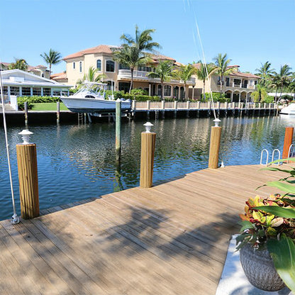 Marina scene with wooden dock, boats, and waterfront houses.