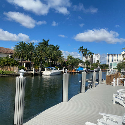Marina scene with boats and a dock under a blue sky with clouds.