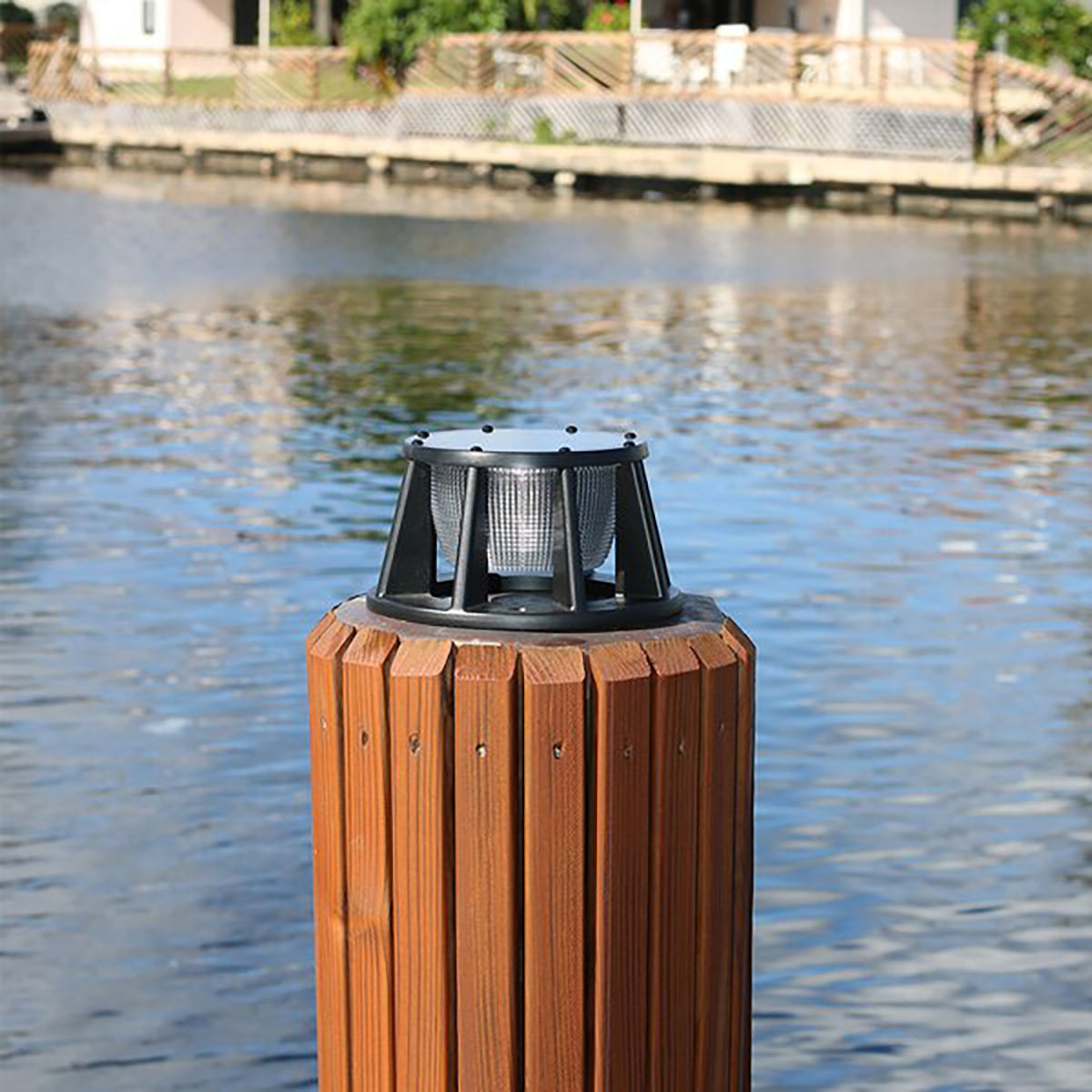 Wooden post with a solar light on top by a body of water