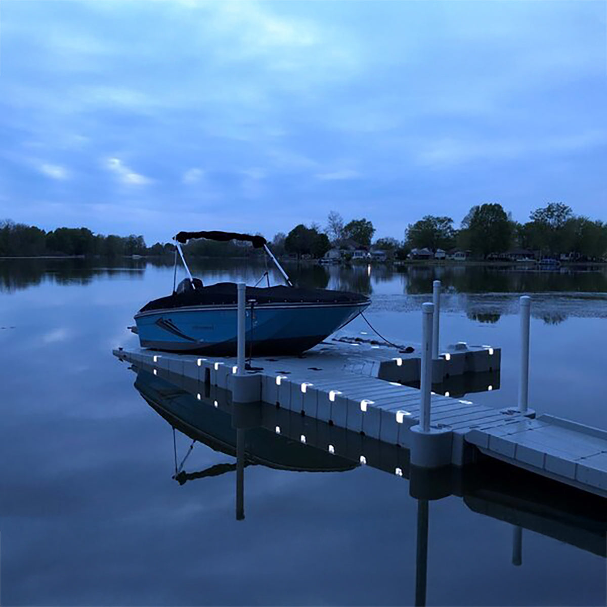 Boat docked at a pier on a calm lake at dusk.