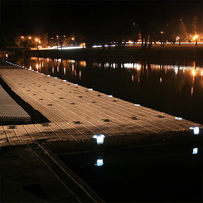 Wooden dock with embedded lights reflecting on water at night