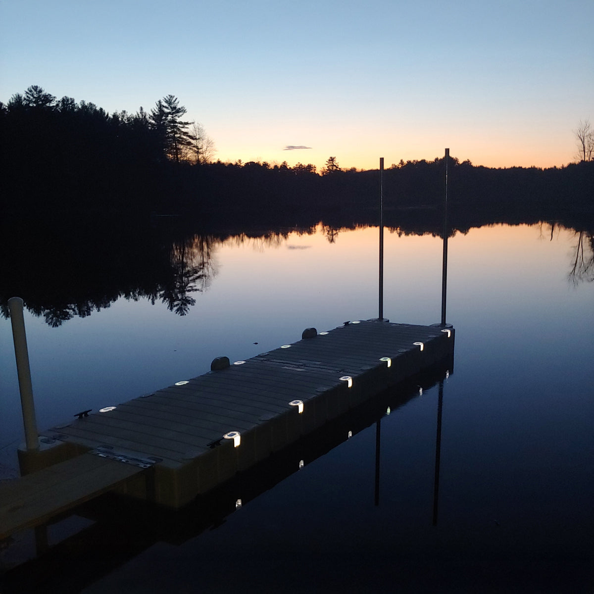 Distant dock on a lake at sunset with trees in the background