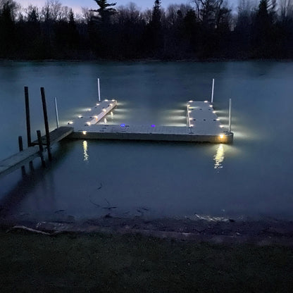 Dock illuminated at night with surrounding trees and water.