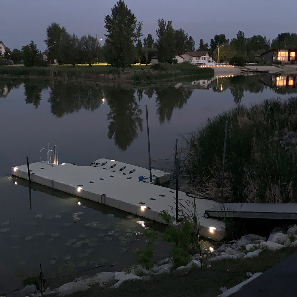 Dock with lights on a calm lake at night