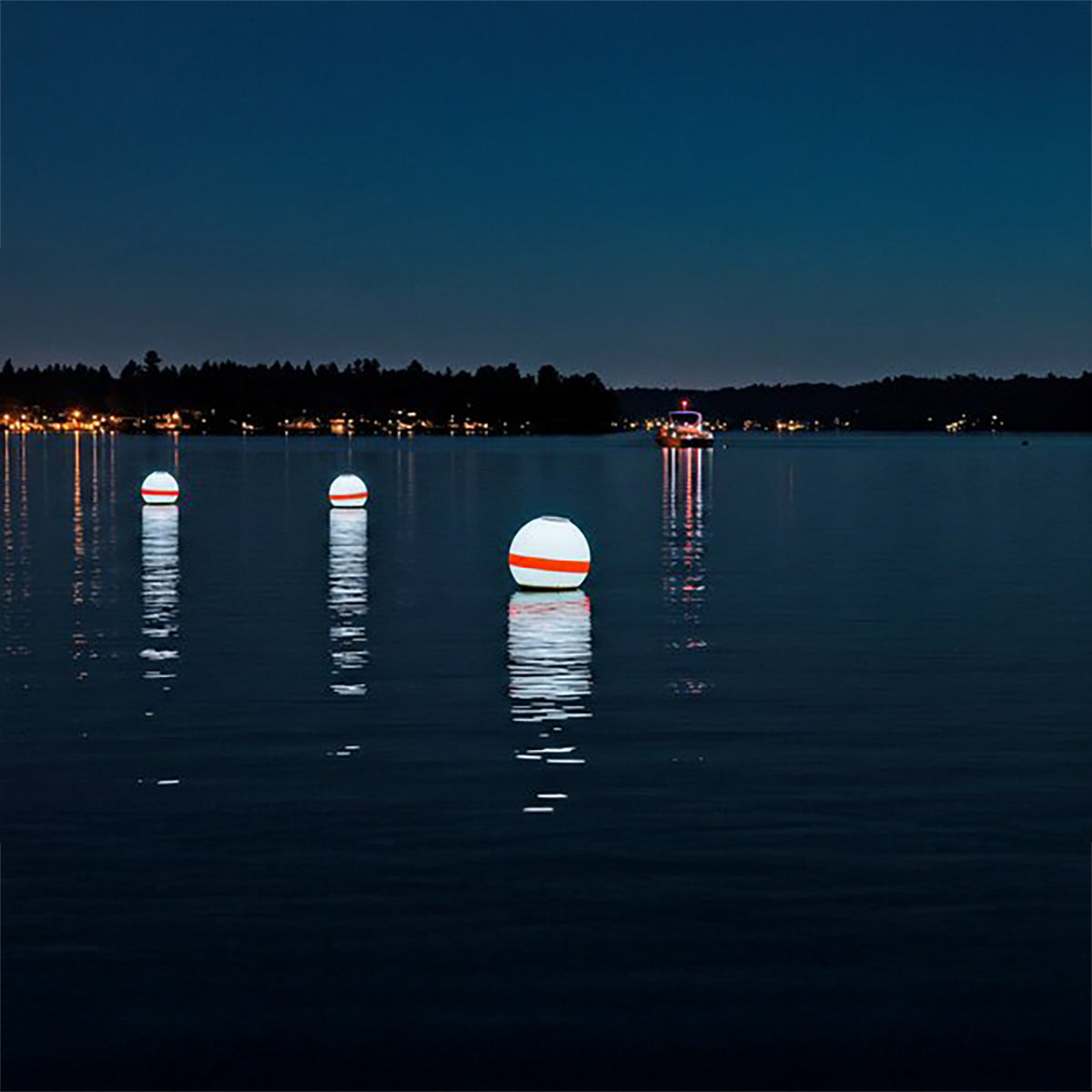Three illuminated buoys on a calm lake at night with a dark sky.