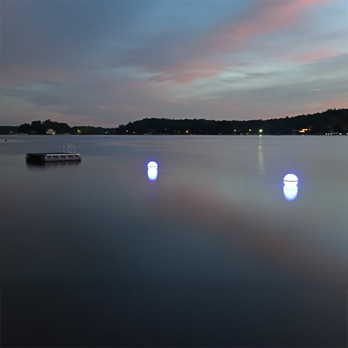 Dusk over a lake with a boat and lights reflecting on the water