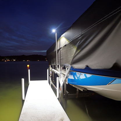 Boat docked at a pier under a dark sky with a light illuminating the area.