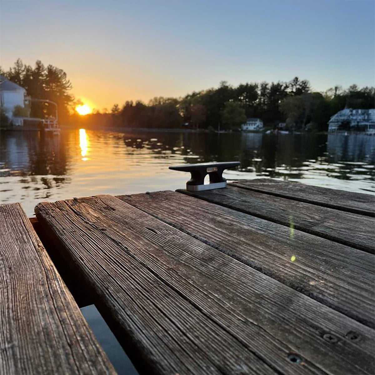 Solar Cleat light mounted to a wooden dock against a sunset background on the lake. 