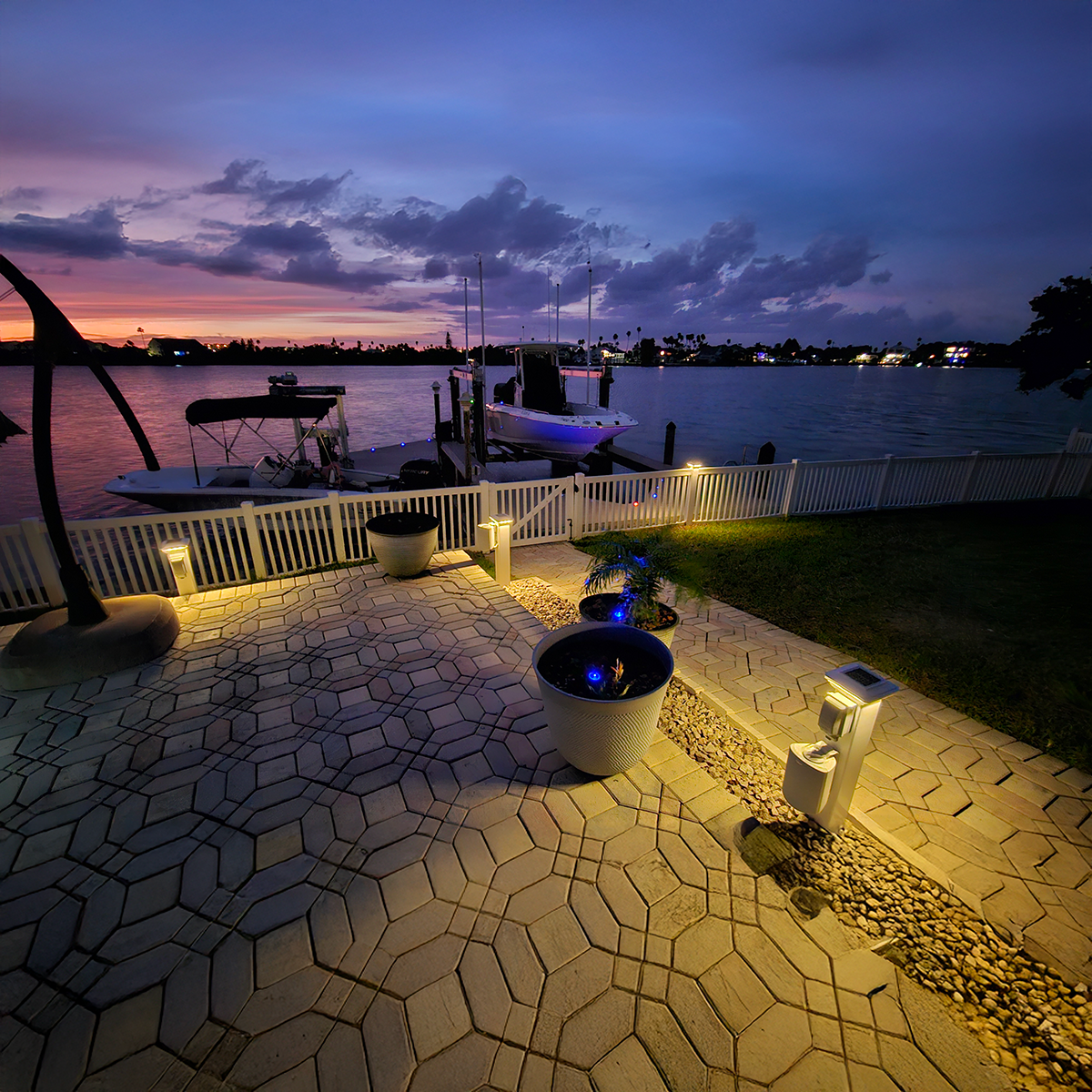 Evening view of a waterfront patio with boats and a colorful sky.