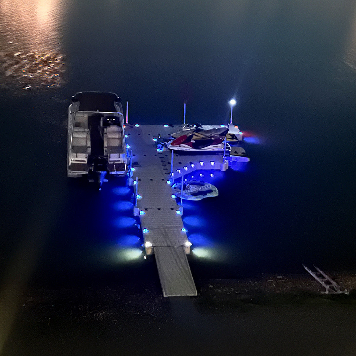 Solar pocket lights glowing blue along an EZ Dock beside boats at night