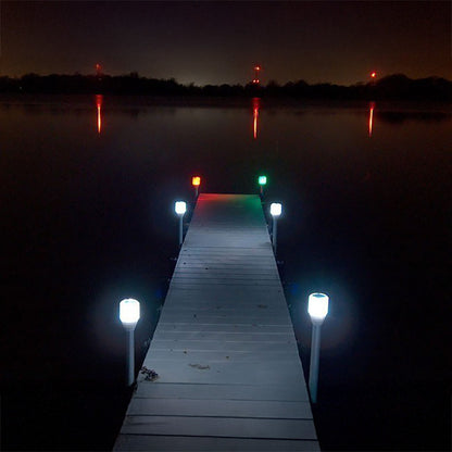 Wooden dock extending into a body of water at night with illuminated lights.