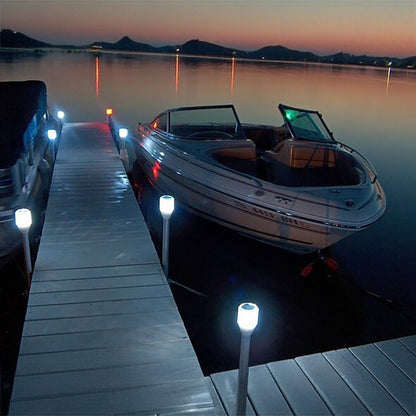 Boat docked at a pier with lights on a calm lake at dusk.